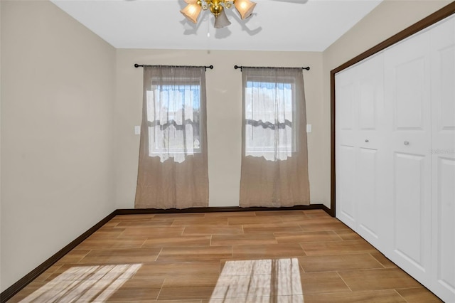 unfurnished bedroom with ceiling fan, baseboards, a closet, and wood tiled floor