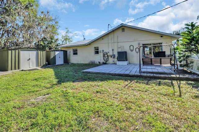 rear view of house featuring a patio, a yard, an outbuilding, and a shed