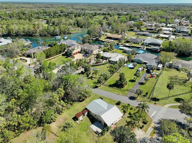 drone / aerial view featuring a forest view, a water view, and a residential view