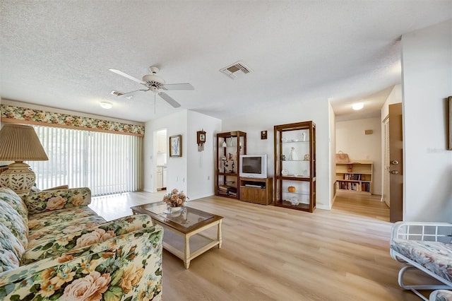 8420 Winding Wood Dr, Port Richey, FL 34668 - living area featuring light wood-style flooring, visible vents, ceiling fan, and a textured ceiling