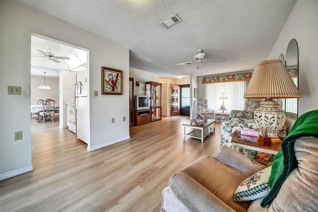 8420 Winding Wood Dr, Port Richey, FL 34668 - living room featuring light wood-style floors, visible vents, a textured ceiling, and a ceiling fan