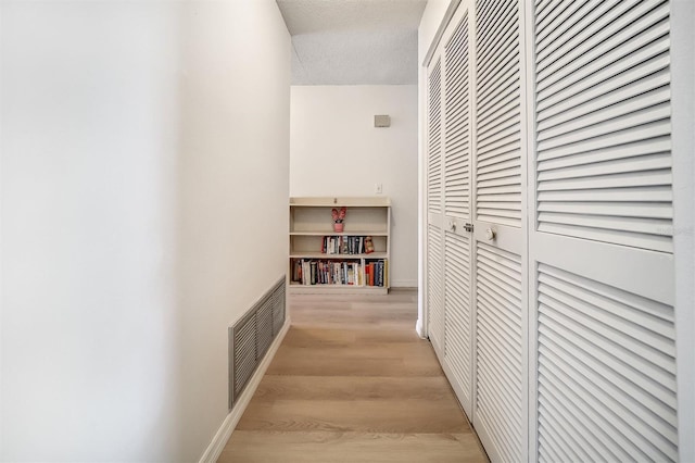 8420 Winding Wood Dr, Port Richey, FL 34668 - hall with light wood finished floors, baseboards, visible vents, and a textured ceiling