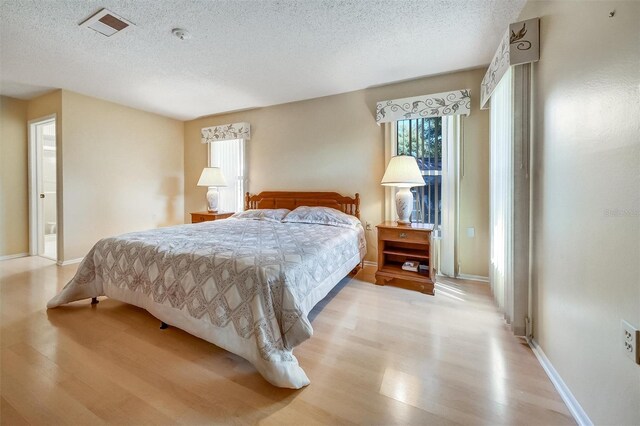 8420 Winding Wood Dr, Port Richey, FL 34668 - bedroom featuring baseboards, light wood-style flooring, visible vents, and a textured ceiling
