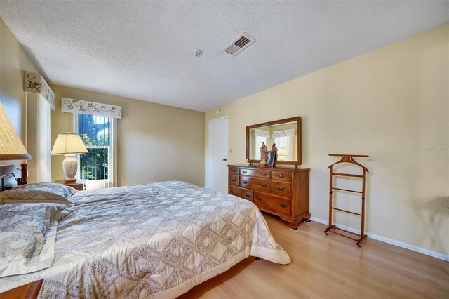 8420 Winding Wood Dr, Port Richey, FL 34668 - bedroom featuring baseboards, visible vents, a textured ceiling, and light wood finished floors