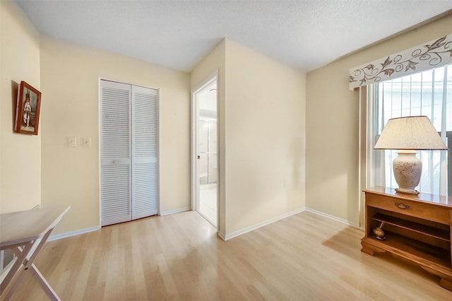 8420 Winding Wood Dr, Port Richey, FL 34668 - unfurnished bedroom featuring a textured ceiling, a closet, wood finished floors, and baseboards