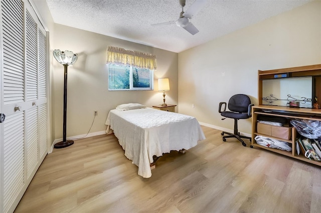 8420 Winding Wood Dr, Port Richey, FL 34668 - bedroom with light wood finished floors, a closet, baseboards, and a textured ceiling