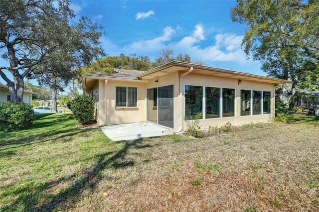 8420 Winding Wood Dr, Port Richey, FL 34668 - rear view of property featuring a sunroom, a patio area, a lawn, and stucco siding
