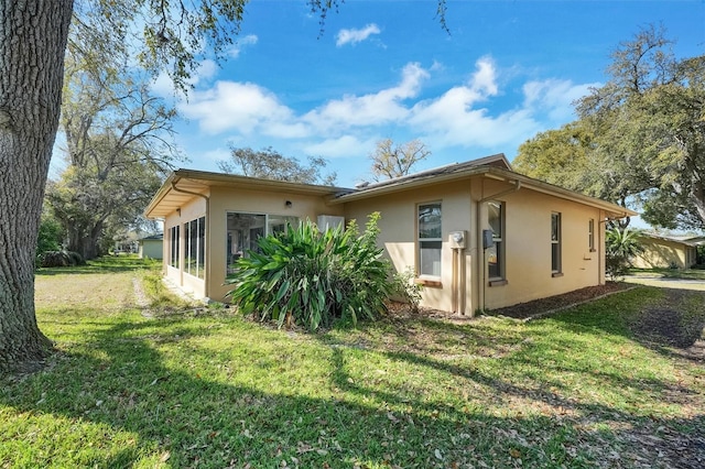 8420 Winding Wood Dr, Port Richey, FL 34668 - view of side of property featuring a lawn, a sunroom, and stucco siding