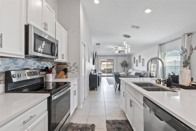 kitchen featuring visible vents, a sink, stainless steel appliances, light tile patterned flooring, and decorative backsplash