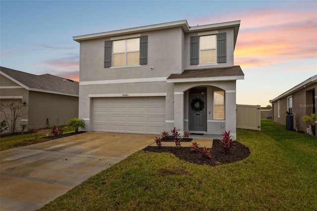 traditional-style house featuring a garage, driveway, a lawn, and stucco siding