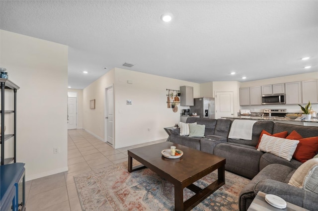 living area featuring a textured ceiling, light tile patterned flooring, recessed lighting, visible vents, and baseboards