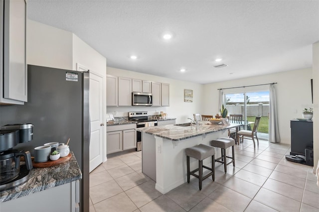 kitchen with a kitchen bar, appliances with stainless steel finishes, gray cabinets, and a sink