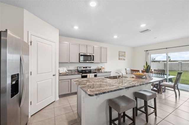 kitchen with appliances with stainless steel finishes, visible vents, a sink, and gray cabinetry