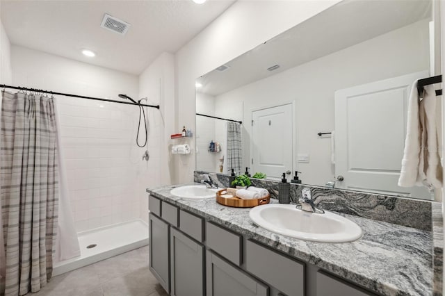 bathroom with double vanity, a stall shower, visible vents, and a sink