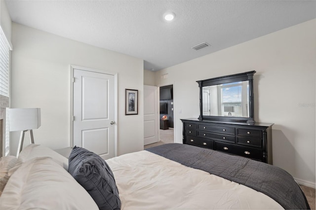 bedroom with a textured ceiling, carpet, visible vents, and baseboards