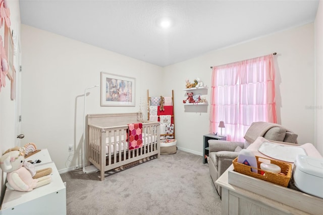 bedroom featuring a crib, carpet, and baseboards