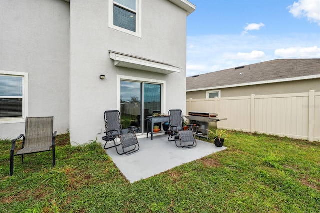 back of house featuring stucco siding, fence, and a lawn