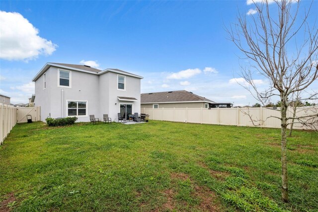 back of property with a yard, a patio area, a fenced backyard, and stucco siding