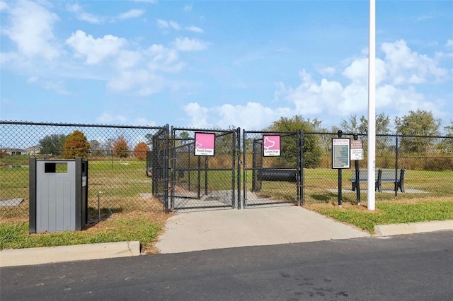 view of gate with fence and a lawn