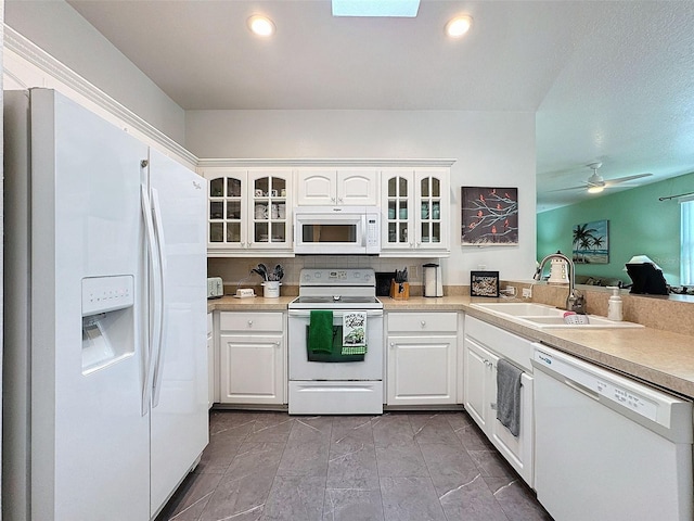 kitchen featuring light countertops, glass insert cabinets, white cabinetry, a sink, and white appliances