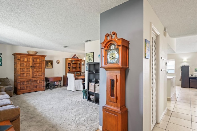 living room with light tile patterned floors, a textured ceiling, visible vents, and light colored carpet