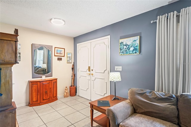 entrance foyer featuring a textured ceiling, baseboards, and light tile patterned floors