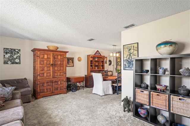 living area with carpet floors, an inviting chandelier, visible vents, and a textured ceiling