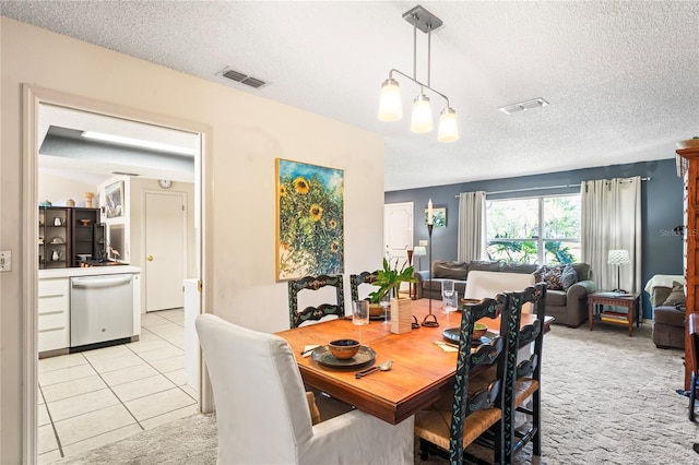 dining area with visible vents, a textured ceiling, and light tile patterned floors