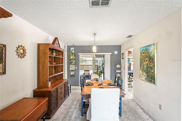 carpeted dining space with visible vents and a textured ceiling