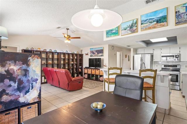 dining room with lofted ceiling, light tile patterned floors, a ceiling fan, and a textured ceiling