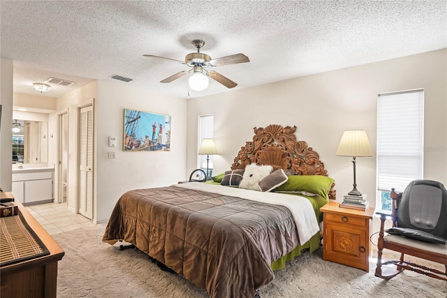 bedroom featuring light carpet, a closet, a textured ceiling, and visible vents