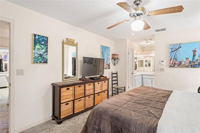 bedroom featuring visible vents, ensuite bathroom, a textured ceiling, and light colored carpet