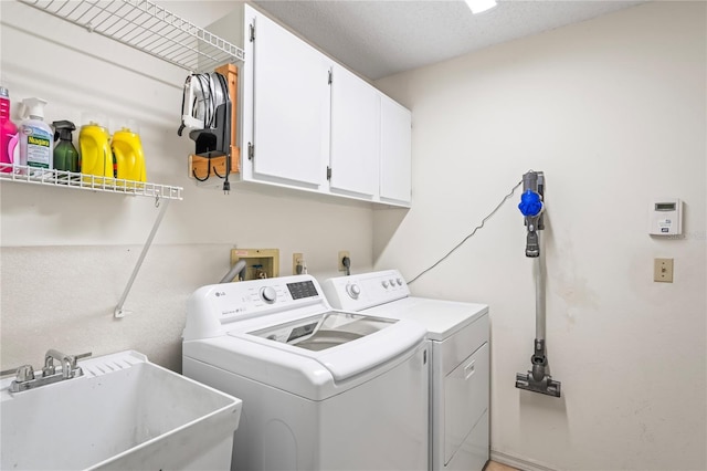 clothes washing area with cabinet space, a sink, and washing machine and clothes dryer