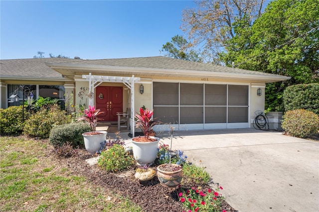 view of front facade with an attached garage, a shingled roof, driveway, a pergola, and stucco siding