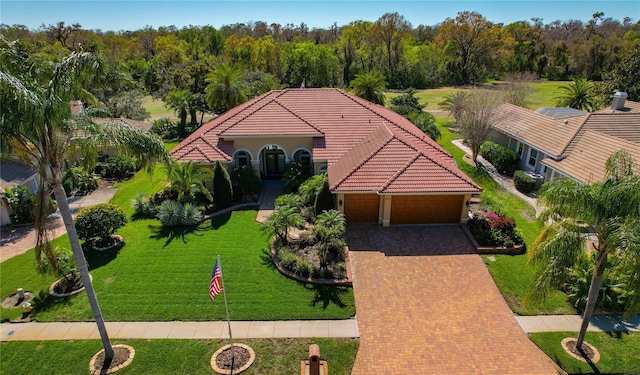 view of front facade featuring a tiled roof, a front lawn, decorative driveway, and a garage