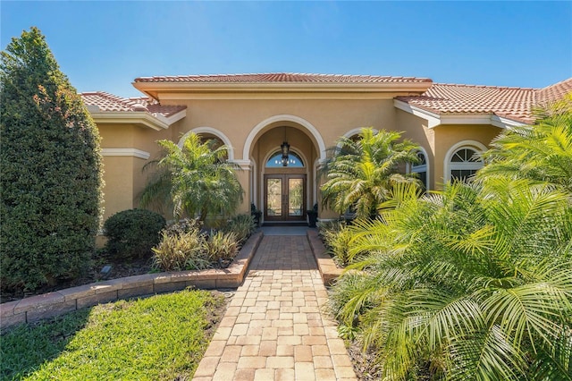 doorway to property with a tiled roof, french doors, and stucco siding