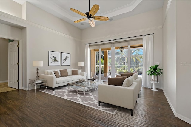living room with baseboards, a tray ceiling, a ceiling fan, and wood finished floors