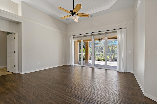 empty room featuring dark wood-type flooring, baseboards, a tray ceiling, and ceiling fan