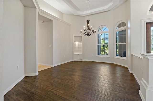 spare room with baseboards, a tray ceiling, a towering ceiling, dark wood-style floors, and a notable chandelier