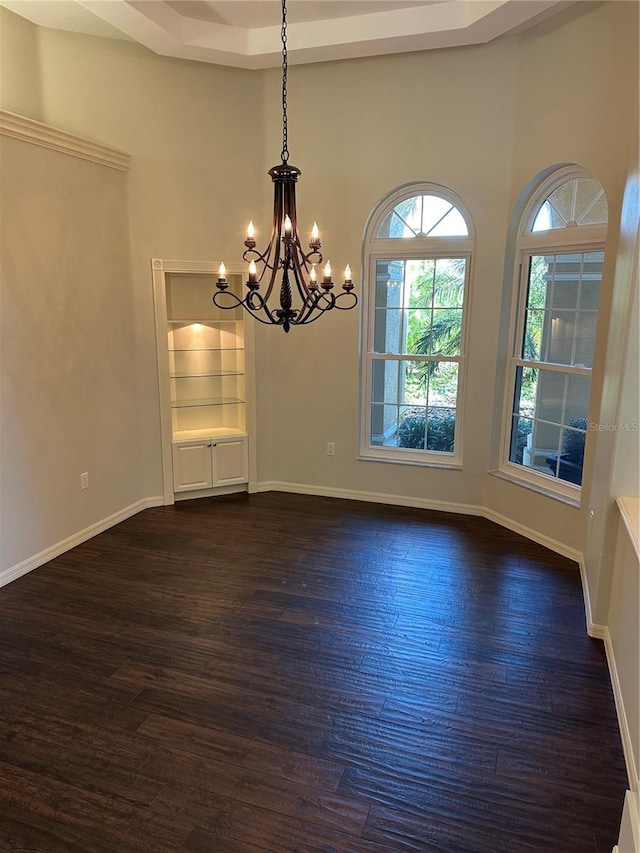 empty room featuring baseboards, a notable chandelier, and dark wood-style flooring