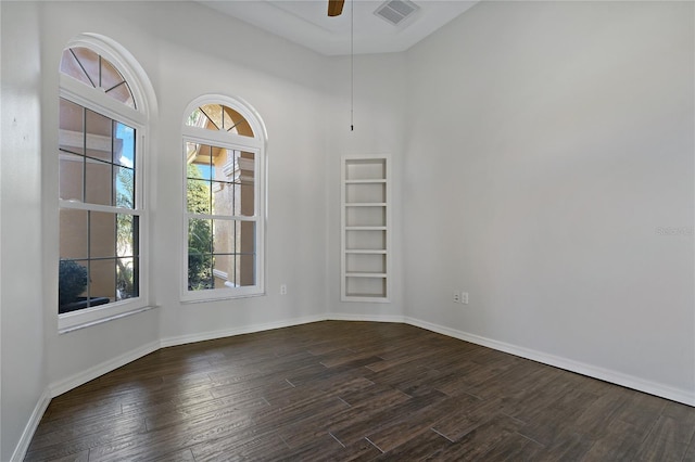 empty room featuring visible vents, baseboards, a ceiling fan, and dark wood-style flooring