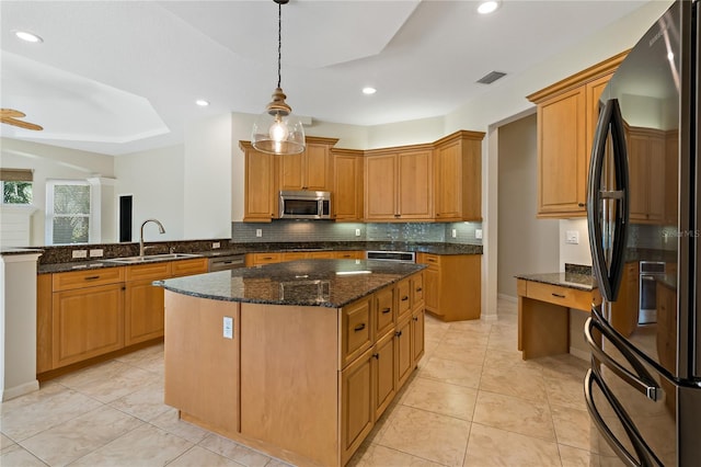 kitchen featuring visible vents, a center island, dark stone counters, appliances with stainless steel finishes, and a sink