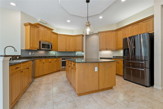 kitchen featuring a sink, backsplash, a center island, dark stone counters, and appliances with stainless steel finishes