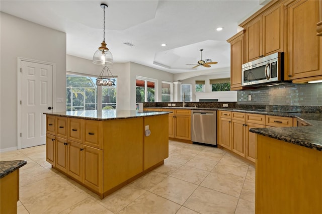 kitchen with dark stone countertops, a tray ceiling, tasteful backsplash, stainless steel appliances, and a peninsula