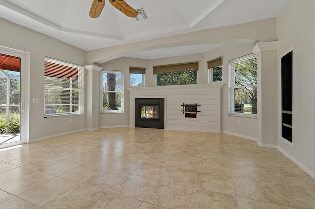unfurnished living room with a tiled fireplace, baseboards, and a wealth of natural light