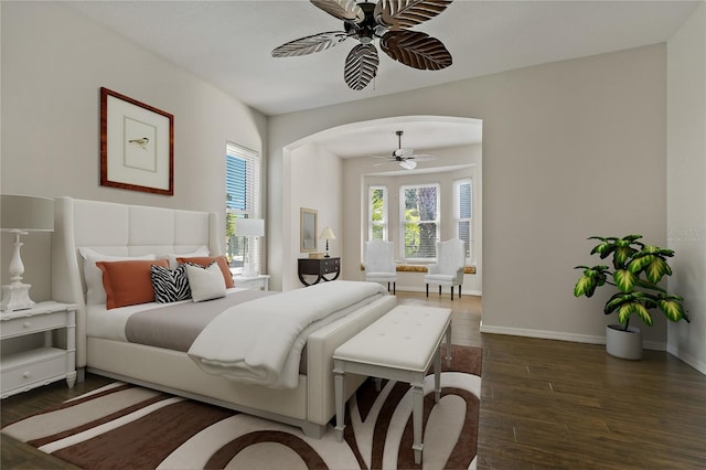 bedroom featuring ceiling fan, wood finished floors, arched walkways, and baseboards