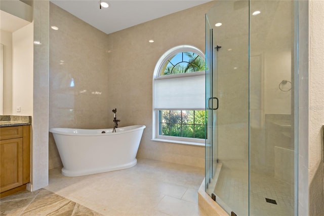 bathroom featuring vanity, a shower stall, a freestanding tub, and tile walls