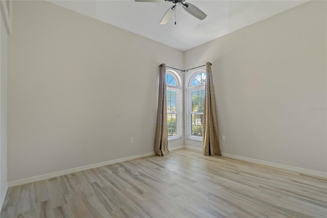 empty room with a ceiling fan, light wood-style floors, and baseboards