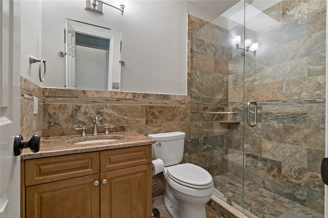 full bath featuring a shower stall, vanity, toilet, and tile walls