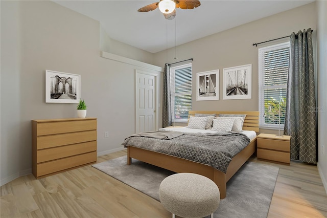 bedroom with ceiling fan, light wood-type flooring, and baseboards
